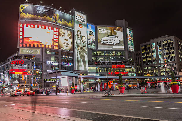 Yonge and Dundas square Toronto, Canada - October 15, 2013:  Yonge and Dundas square in Toronto at night, showing many colourful neon billboards with advertisments and the blur of traffic and people going past toronto dundas square stock pictures, royalty-free photos & images