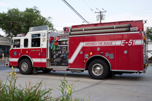 Greenwich, USA - July 7, 2012: City scene of a fire truck going on a call from the downtown business area of the town of Old Greenwich, Connecticut.