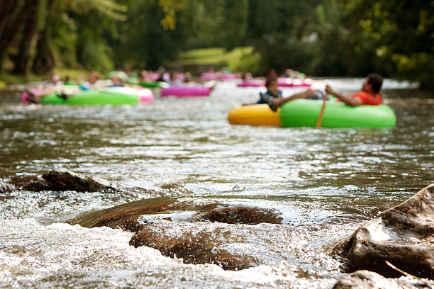 Defocused People Tubing Down RiverApproach Boulders In Focus Helen, GA, USA - August 24, 2013:  Defocused people enjoy tubing down the Chattahoochee River in North Georgia on a warm summer afternoon, as river boulders in foreground are in focus. inflatable ring photos stock pictures, royalty-free photos & images