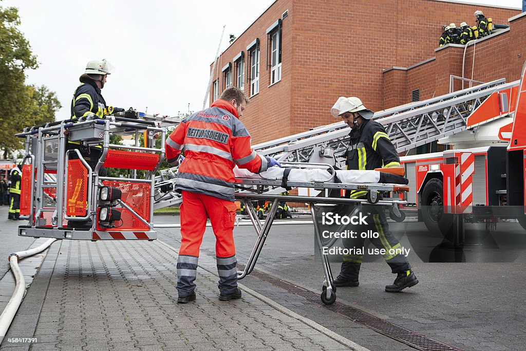 German firefighters and ambulance service Wiesbaden, Germany - September 14, 2013: Fully equipped german firefighters and member of ambulance service are preparing a stretcher for transportation at the scene of a simulated burning building during fire training exercise at fire brigade Wiesbaden, Germany Paramedic Stock Photo