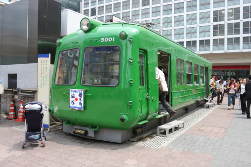 Tokyo, Japan - June, 10th 2008 : This old train was displayed at the Shibuya, Tokyo , Japan. This train was used by Tokyu Corporation. A person is going into the train to visit. Many people walking at the street.