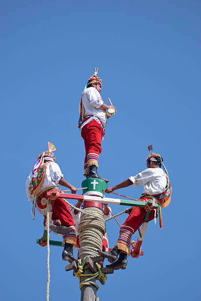 Teotihuacan, Mexico - December 30, 2008: Representation of the ritual Dance of the flyers. This ritual was originated in the central part of Mexico, and spread through all Mesoamerica. The dance of the Flyers in spanish: Danza de los Voladores was a ritual to provide for fertility. Four dancers representing the Cardinal points launch themselves from a 30 meter pole tied with a rope, while the fifth one plays an instrument. The descent represents the rain fall.
