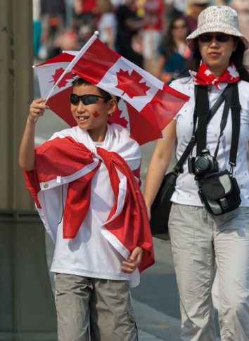 Ottawa, Canada - July 1, 2013: An Asian boy waving a Canadian flag during Canada Day in downtown Ottawa, Ontario.