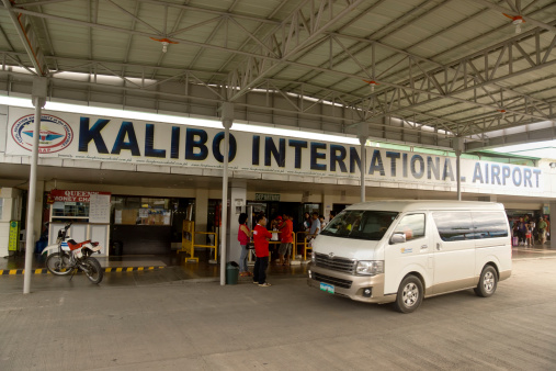 Kalibo, Philippines - September 18, 2013: A van drives past passengers queueing to enter the departure terminal at Kalibo International Airport. Kalibo is used by many passengers travelling onwards to Boracay Island, one of the Philippines's top tourist draws.