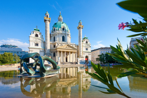 Vienna, Austria - August 8, 2010: The St. Charles's Church (Karlskirche) a 18th century baroque church in the centre of Vienna. The majestic landmark is highly frequented by tourists from all over the world. In front the lake with a sculpture from Henry Moore. Photo taken with tilt and shift lenses.