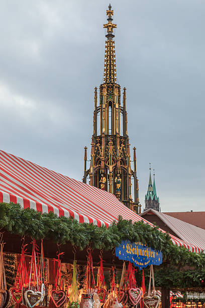 Nuremberg, Germany - December 16, 2012: The Schoner Brunnen stands out among the stalls of the Christmas market in the Hauptplatz, in downtown Nuremberg. The stalls with awnings in red and white stripes form the Germany's oldest Christmas fairs. 