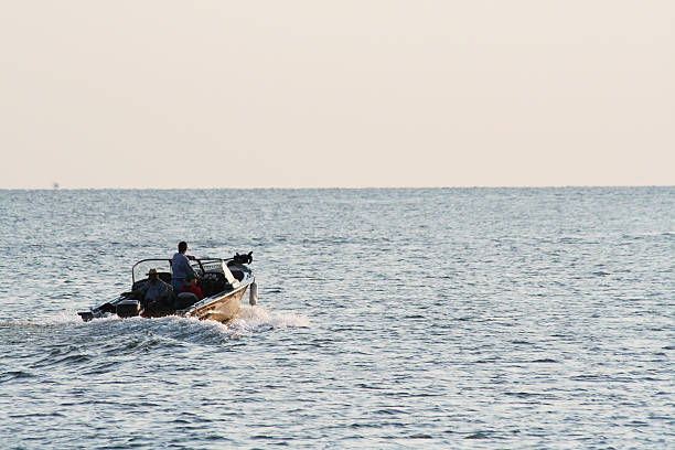 Outboard Motor Boat Headed Out for Fishing Irondequoit, New York, USA - July 8th, 2006: Three fishermen heading out from Irondequoit Bay onto Lake Ontario at dawn. family motorboat stock pictures, royalty-free photos & images