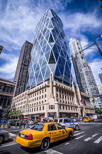 New York City, USA - September 25, 2013: taxicab along with other cars drive past the Hearst Tower. The Hearst Tower is a building located at 300 West 57th Street, near Columbus Circle in Midtown Manhattan