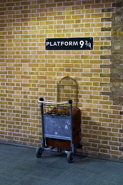 London, United Kingdom  - September 7, 2013: This is the British Rail homage to Harry Potter at Kings Cross station in London England.  A half trolley is embedded in the wall and tourists take pictures of themselves pretending to exit through the wall for the Hogwarts Express. A half bird cage for Hedwig is a recently added feature.