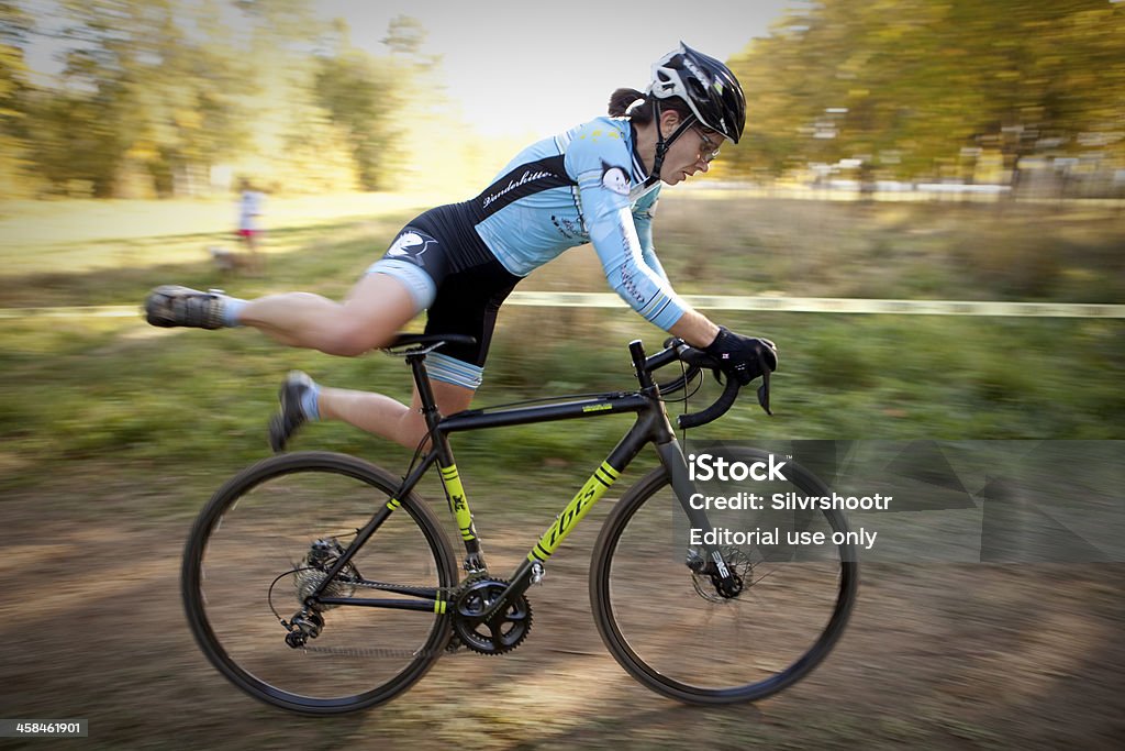 Woman jumping onto her bike during cyclocross race Sandpoint, ID, USA - October 6, 2013: Jumping back onto her bicycle after carrying it over obstacles, this woman is executing one of the harder talents to master at a Cyclocross race. This race was part of the Inland Northwest Cyclocross Series. Bicycle Stock Photo