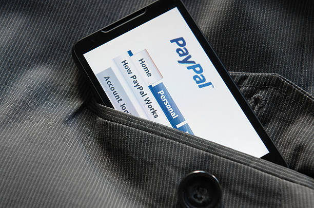 смарт-телефон с paypal.com логотип на кармане - global communications communication digital display google стоковые фото и изображения