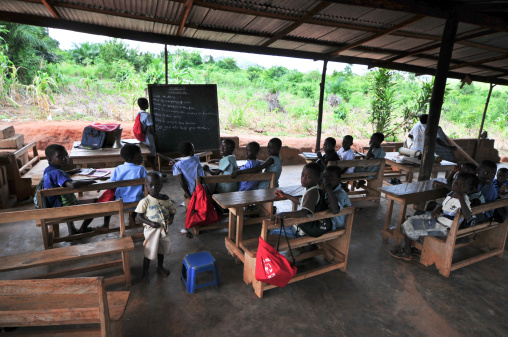 Asiafo Amanfro, Eastern, Ghana - November 14, 2011: Students attending class in an outdoors elementary school classroom in the Yilo Krobo District near Accra, Ghana on November 14, 2011. Mud brick building.