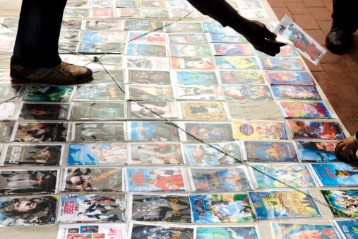 Sabadell, Spain - April 3, 2011:Man selling pirated dvds in the street. The dvds, displayed on the floor and wrapped in plastic, sell for two or three euros, and mostly are recent movie titles. Althought illegal, sometimes this activity is tolerated in Spain.