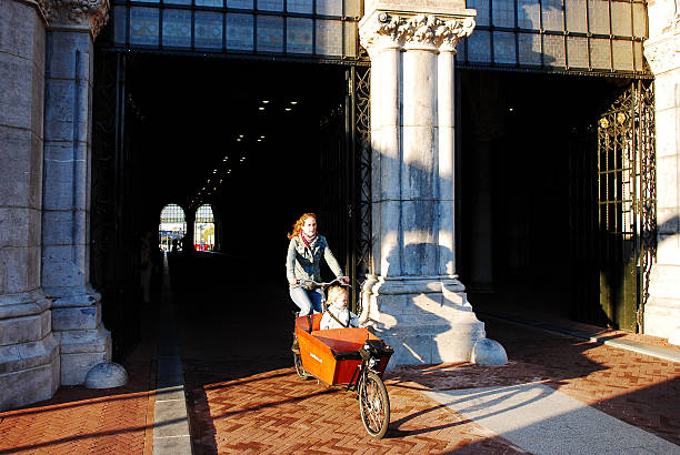 Amsterdam, The Netherlands- Sept 29, 2013: Early morning shot of a mother taking her child to school on a bicycle trough the newly renovated underpass of the Rijksmuseum of Amsterdam.