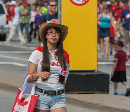 Ottawa, Canada - July 1, 2013: An Asian girl walking down the street during Canada Day in downtown Ottawa, Ontario.