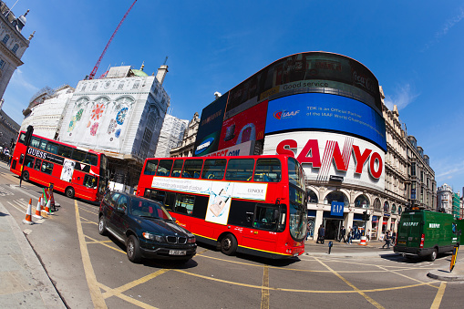 London, England, UK - May 4, 2011: two red busses and a car driving during a bright spring day in Piccadilly Circus, London. Photo taken with a fish-eye lens.