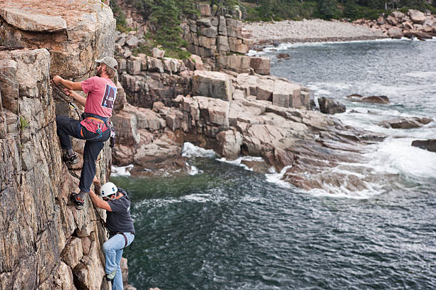 戦士の戦い負傷イベントロッククライミングになれるアカディア国立公園 - climbing men sea cliff ストックフォトと画像