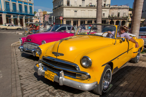 Havana, Cuba - August 8, 2013: Taxi driver in a shiny yellow taxi waiting for customers. The taxi is a classic Chevrolet . More than one third of the cuban cars are american vintage cars from the 50s and 60s and many function as taxi.