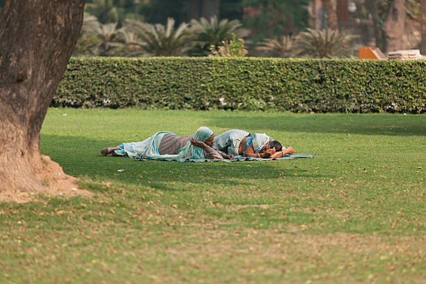 barefoot family lie on their backs in the green grass in a sunny spring park.