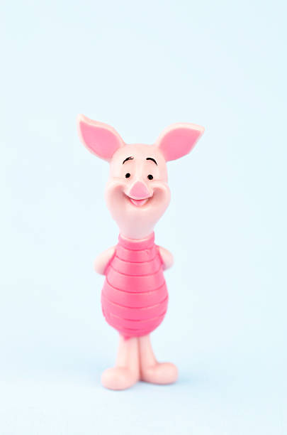 Suffolk, Virginia, USA - April 30, 2011: A vertical studio shot of the fictional character Piglet, who was originally created by the author A.A. Milne in the Winnie the Pooh Series of books. Here Piglet is standing looking at the camera with his hands behind his back and is smiling.