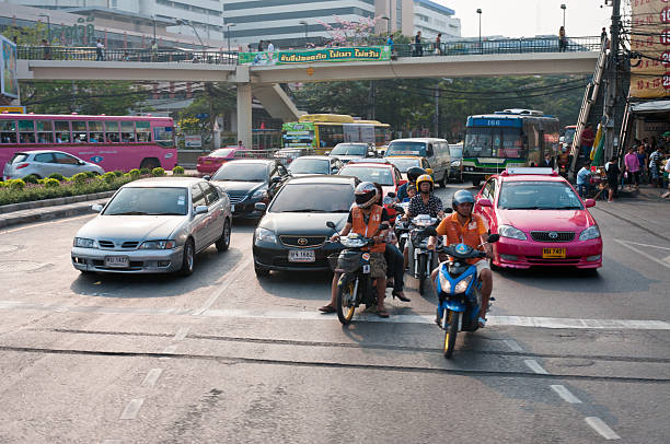 Bangkok, Thailand - March 3, 2011: Motorcycles and cars waiting at a busy junction with pedestrians in the background near Victory Monument in Bangkok, Thailand.
