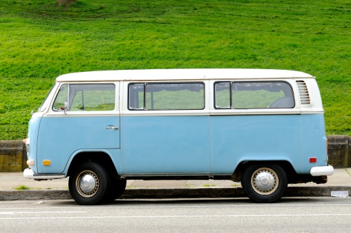 San Francisco, United States - March 26, 2012: A vintage, blue Volkswagen Bus is parked next to a hill covered in bright green grass at the Alamo Square Park.