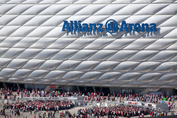 Allianz Arena before a soccer match Munich, Germany - April 2, 2011: The soccer stadium Allianz Arena in Munich before the soccer match FC Bayern M&amp;uuml;nchen against Borussia M&amp;ouml;nchengladbach (German Soccer League - Bundesliga). Fans approach the stadium coming from the nearby underground station and gathering at the access control. Police patrolling with vans.  Architects of the stadium: Herzog de Meuron. The capacity of the stadium is 69,901 spectators. The facade is constructed of 2,874 foil air panels. Two Munich soccer teams play in this stadium and the air panels can be illuminated in the colors of the respective team, either red for "FC Bayern M&amp;uuml;nchen" or blue for "1860 M&amp;uuml;nchen". The stadium is the venue for the 2012 final of the UEFA Champions League. allianz arena stock pictures, royalty-free photos & images