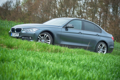 Breuberg, Germany- April 21, 2013: 2013 BMW 3 Series (320d) parked outside in a suburban grass field. The BMW 3-Series is a compact executive car produced by the German car manufacturer BMW.  BMW (Bayerische Motorenwerke AG) is a german automobile manufacturing company based in Munich, Bavaria. Some motion blur. This is the 2013 Sport Line edition.