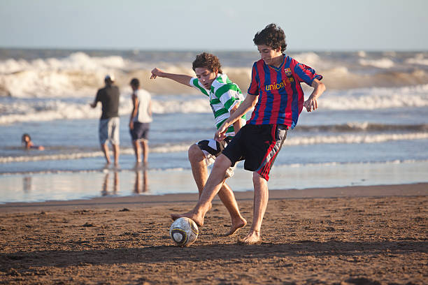 deux garçons jouant au soccer sur la plage en argentine - barcelona fc photos photos et images de collection