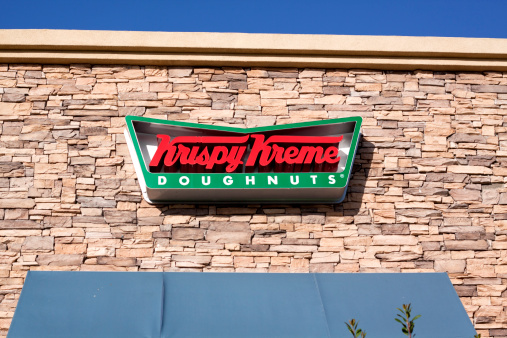 Chula Vista, USA - April 29, 2011: Red and green Krispy Kreme Doughnuts Sign as viewed from the sidewalk.  The building exterior is made of stone with blue awnings for each store window.  Krispy Kreme Doughnuts have been in business serving doughnuts and coffee since 1937.  Krispy Kreme Doughnut stores operate in 14 countries around the globe.