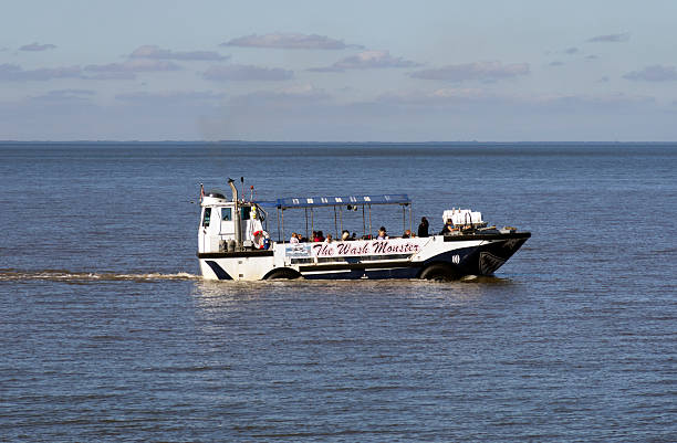 The Wash Monster at Hunstanton Hunstanton, England - September 22, 2013: Holidaymakers travelling in aEThe Wash Monsteraa at Hunstanton in West Norfolk, England. aEWiley The Wash Monsteraa is an amphibious vehicle which operates tours along this coast  to see the famous striped cliffs and seal colonies and is an old US amphibious craft which was originally used for landing troops on the beaches of Vietnam during the Vietnam War. The coast of Lincolnshire can be seen across The Wash. (Bright sunlight.) amphibious vehicle stock pictures, royalty-free photos & images