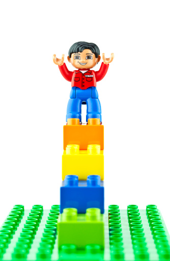 Suffolk, Virginia, USA - April 12, 2011: A vertical studio shot of Lego brand Duplo bricks built into a staircase shape with a Duplo man standing on top of them.