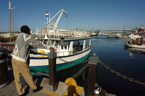 Cape Town, South Africa - October 14, 2006: A black man looks out to the port of Cape Town at the Victoria and Albert Waterfront.