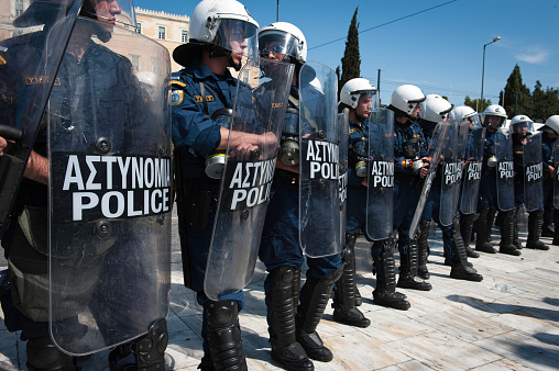 Athens, Greece - May 11, 2011:  Greek riot police with shields, gas masks, clubs stand at Syntagma, Square with the Parliament building in the background. 