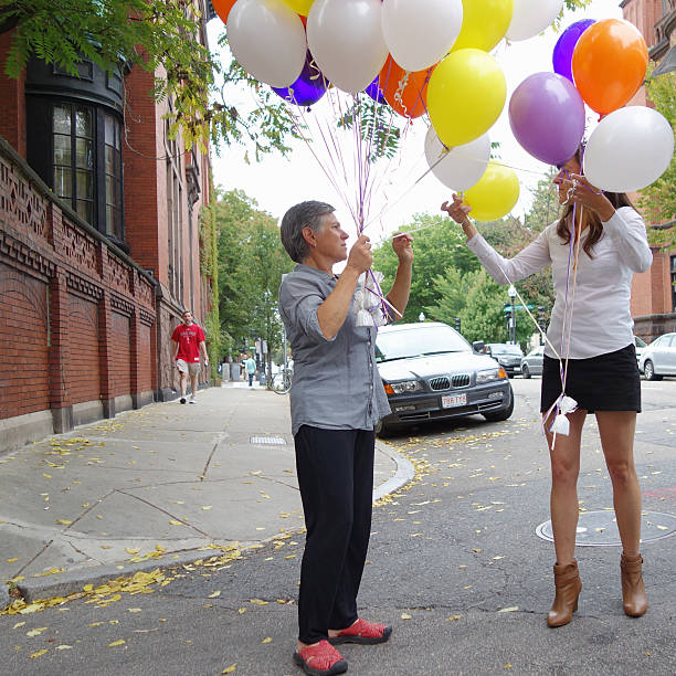 Two females holding colorful balloons stock photo
