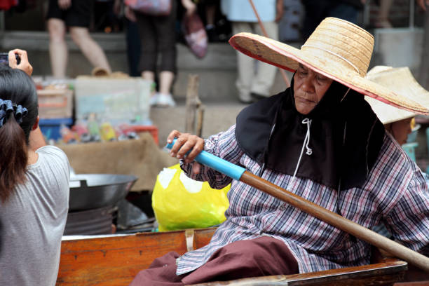 Rowing Damnoen Saduak,Thailand - April 22, 2011: An old woman paddles at the Damnoen Saduak Floating Market mode of transport rowing rural scene retail stock pictures, royalty-free photos & images