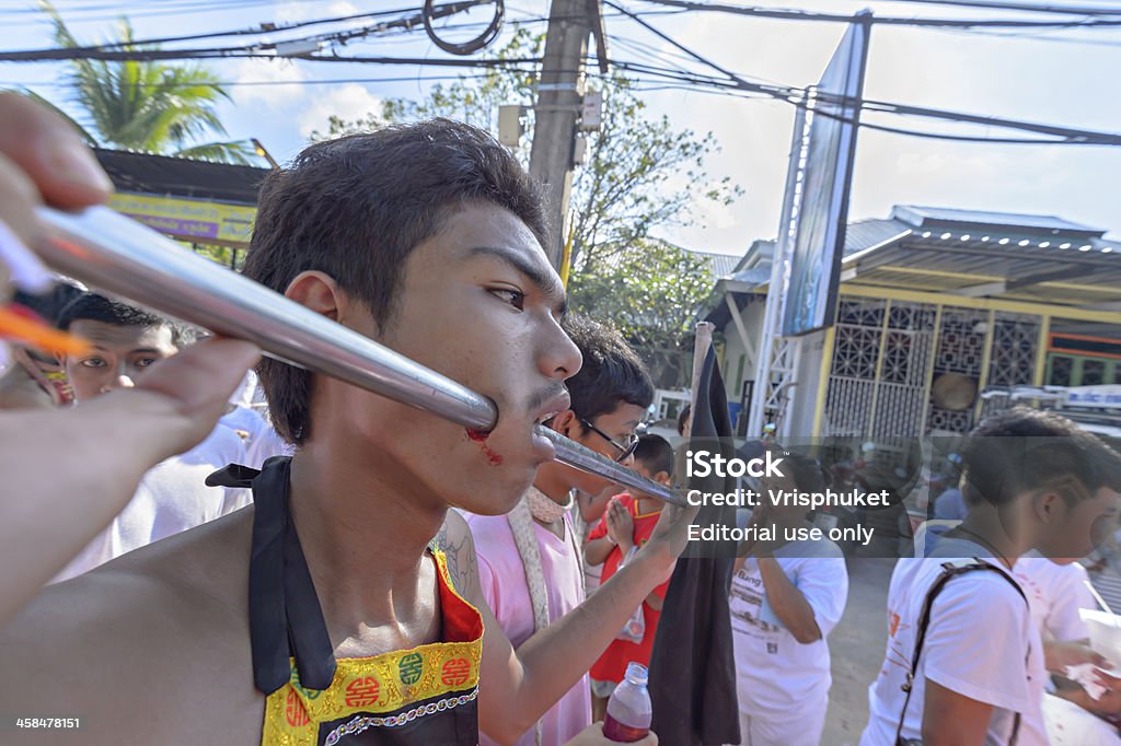 Phuket Province vegetarian festival Phuket, Thailand- October 11, 2013: an unidentified Chinese monk possessed by his god walks with his mouth pierced in the Phuket Vegetarian Festival. Adult Stock Photo