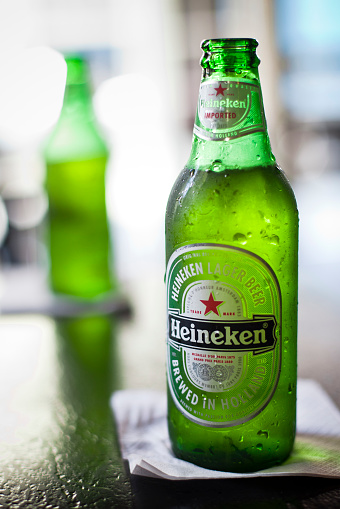 New Orleans, Louisiana, USA - March 28, 2011: An indoor product shot of two Heineken beers setting on a table. All bottles are opened and fresh from ice cooler with wet condensation visible on bottles. Heineken is a premium brand lager beer brewed in Holland by the Heineken Brewing Company.