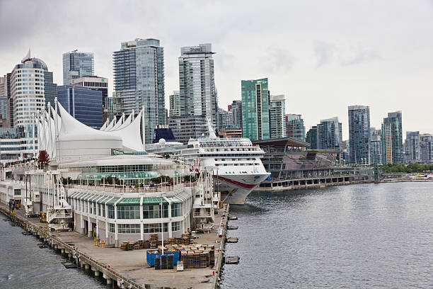 Vancouver - September 16, 2013: View of Canada Place cruise dock as seen from the waters of Coal Harbour in Vancouver.  The characteristic white sails are visible to the left of the image and a cruise ship can be seen tied up in the middle of the image.  Behind the cruise ship are the high rises of downtown Vancouver as well as the harbour side convention centre.  Typical of most times when cruise ships sail from Canada Place, many spectators can be seen along the upper level walkway in the centre of the image.  Image was taken around 5:00pm on an overcast day.