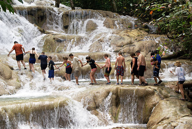 Climbing Dunns River Falls Ocho Rios, Jamaica - February 21, 2008: Dunns River Falls is a popular tourist destination in Jamaica. The challenge is to climb the cascades as a group. dunns river falls stock pictures, royalty-free photos & images