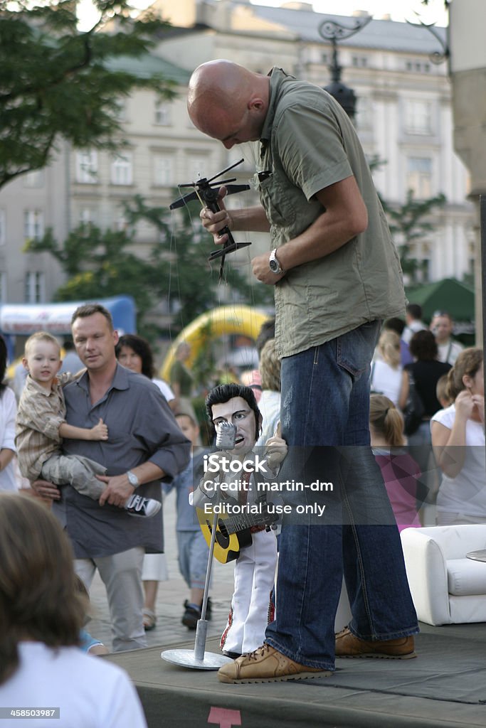 Elvis Presley show Krakow,Poland - August 2, 2006: Man holding  an Elvis Presley marionette on a string  imitating a singing.  Elvis Presley music is playing all the time during the performance.The event is taking place on the Main Market square of Krakow and many people are watching the attraction. Actor Stock Photo