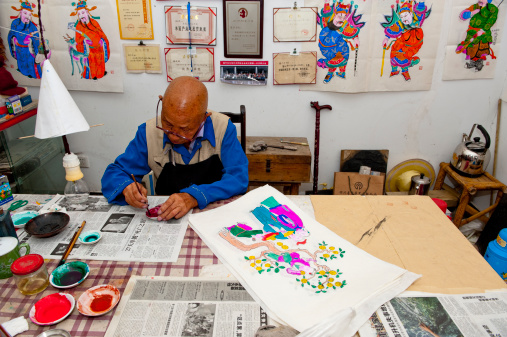 Mianzhu, China - September 09, 2010: A senior chinese man is painting the traditional New Year pictures in a village of Mianzhu, Sichuan, which is one of the most famous places producing this art works in China.