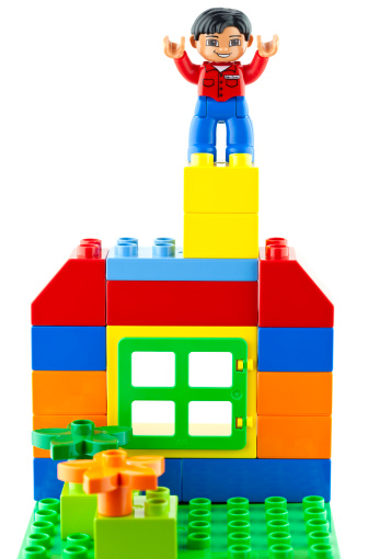 Suffolk, Virginia, USA - April 12, 2011: Studio shot of Lego brand Duplo toy blocks built into a house shape with a Duplo man standing on top of the chimney.