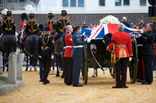London, United Kingdom - April, 17th 2013: The Tri- Service Bearer Party drape the Union Jack over the coffin of Baroness Thatcher at St Clement Danes Church, before it continues it's journey to the funeral service at Saint Paul's Cathedral, carried on a gun carriage of The King's Troop Royal Horse Artillery.