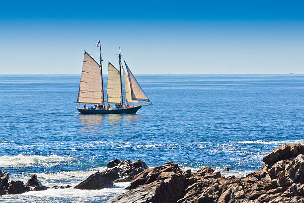 Sailboat is sailing near Kennebunkport, Maine. Kennebunkport, ME, USA - September 19, 2013: Sailboat sailing in Atlantic Ocean. This New England scene is backlitlit by autumn sun. Tourists on board are enjoying the trip. sailboat mast stock pictures, royalty-free photos & images