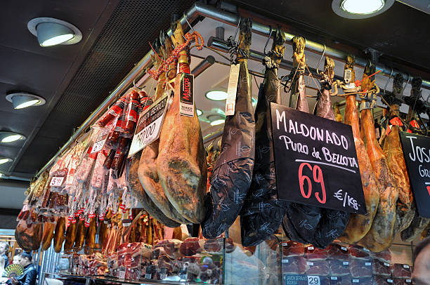 Spanish Pork Barcelona, Spain - April 26, 2013: Barcelona La Boqueria market, during the daytime afternoon. Showing a vendor booths' different cuts of pork for sale, for which Spain is famous. Customers of La Boqueria in the background. cebolla stock pictures, royalty-free photos & images