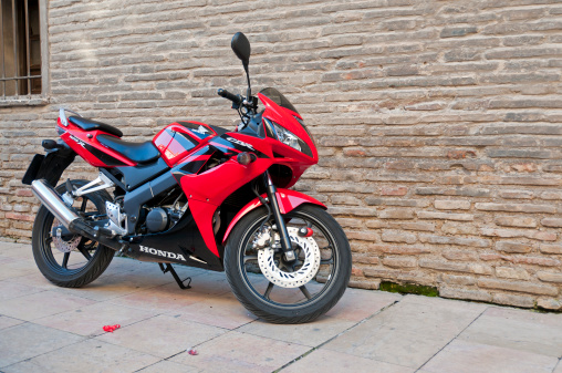 Zaragoza, Spain - March 20, 2011: A black and red Honda CBR125 motorbike parked in a street.