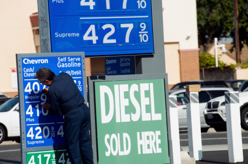 Los Angeles, California, USA - June 6, 2013: A gas station attendant posts the bad news of rising gasoline costs on the stationaas price marquee.
