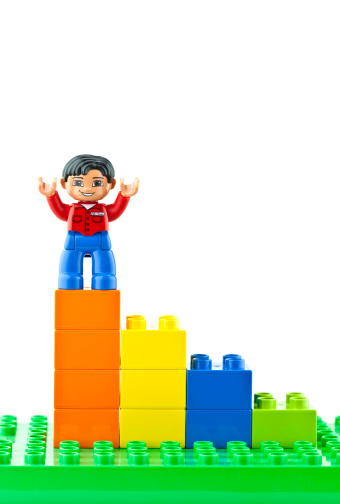 Suffolk, Virginia, USA - April 12, 2011: Studio shot of a conceptual bar graph made with Lego brand Duplo toy blocks, with a Lego man standing on the top bar with his arms outstretched.