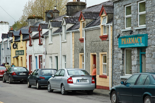 Cong, County Mayo, Ireland- June 4, 2006:A local resident looks out the doorway of her home on a building block in Cong made up of conneceted row houses, a cafe, and a pharmacy.